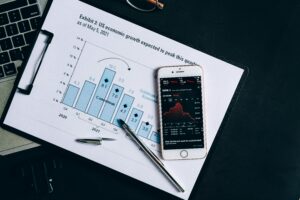 A smartphone displaying stock data rests on a financial report graph.