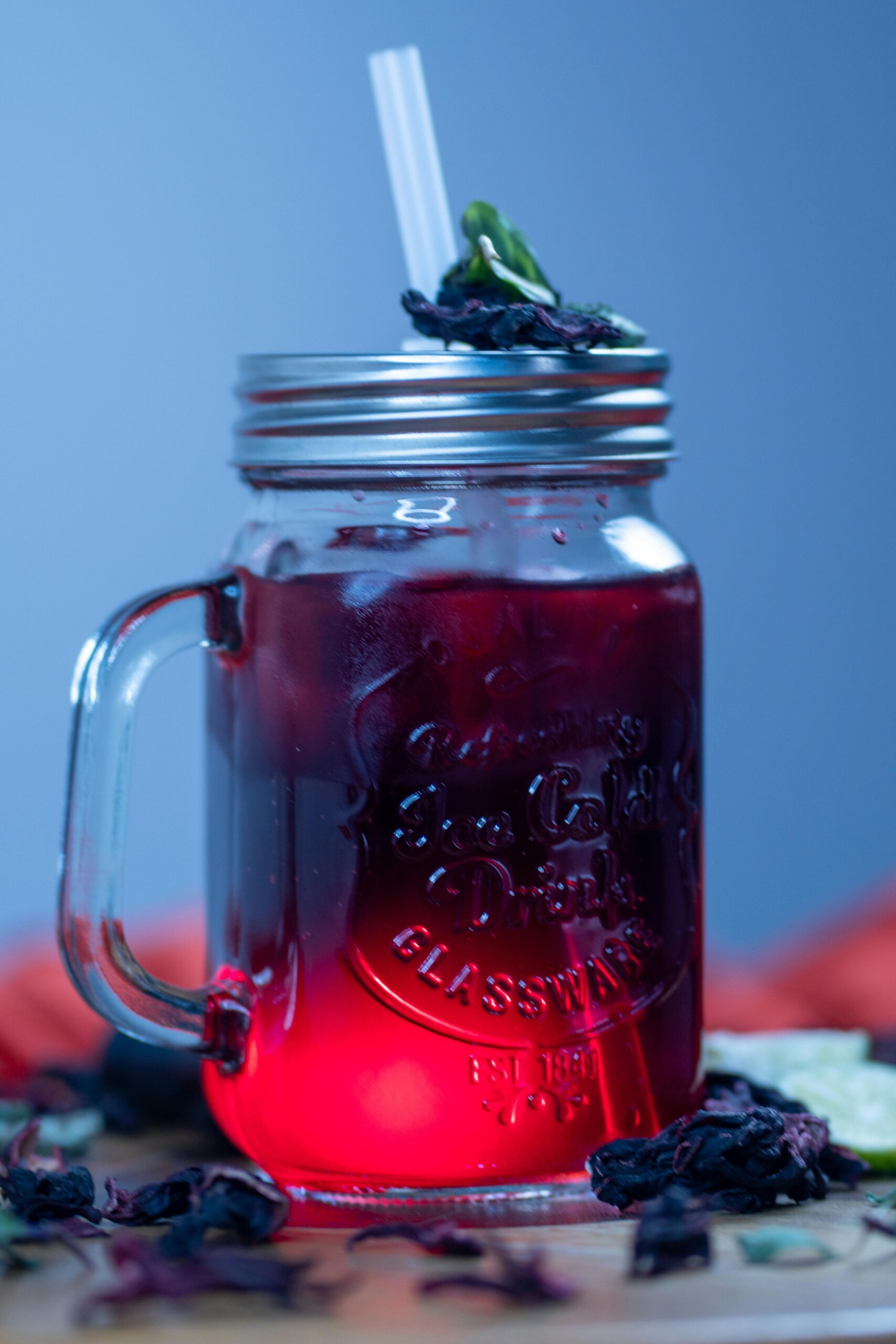 Chilled hibiscus tea in a mason jar with mint and lemon slice, evoking a refreshing summer vibe.